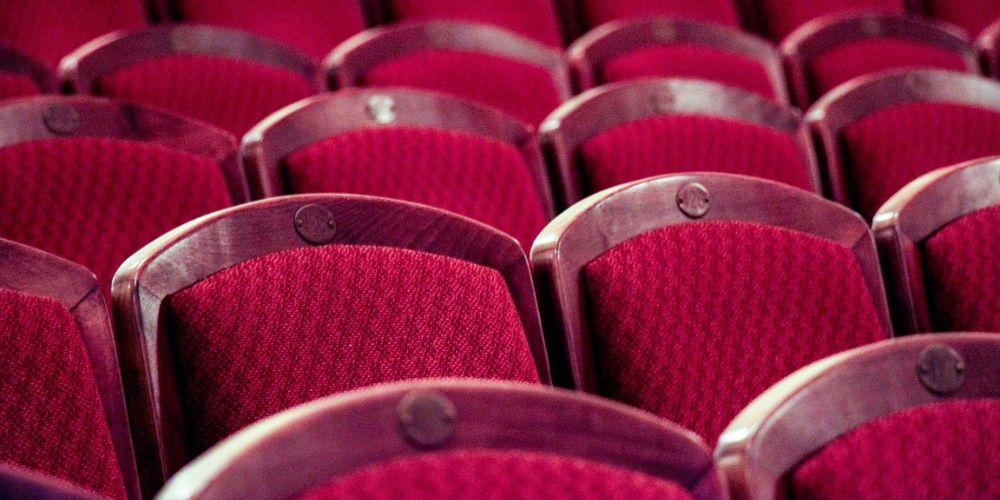 Una fila de butacas de color rojo en una sala de cine