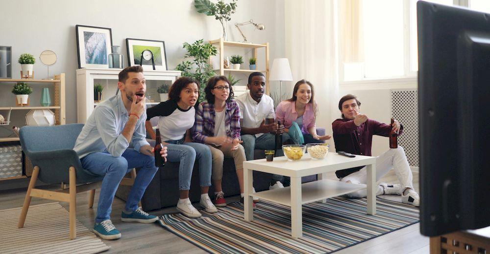 Un grupo de amigos está reunido en el sofá mientras ven un partido de fútbol