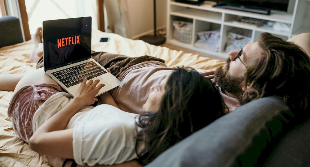 Una pareja disfruta de Netflix tumbados en la cama