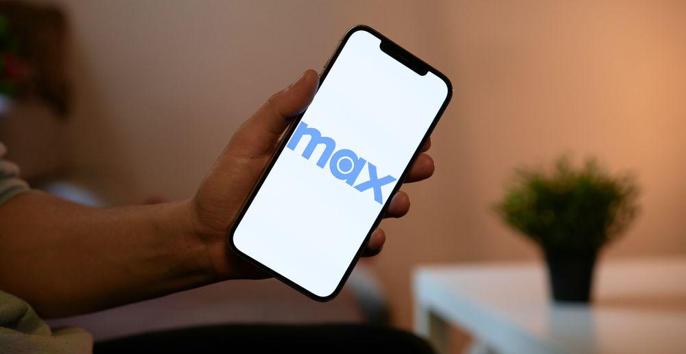 Sujetando un teléfono móvil con el logo de Max en pantalla