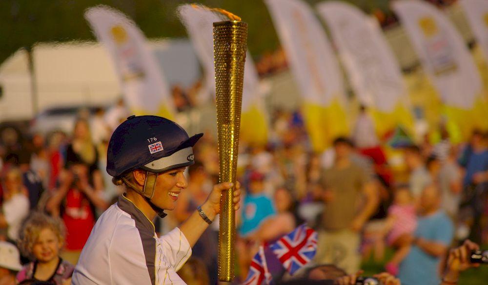 Una atleta transportando la llama olímpica por las calles