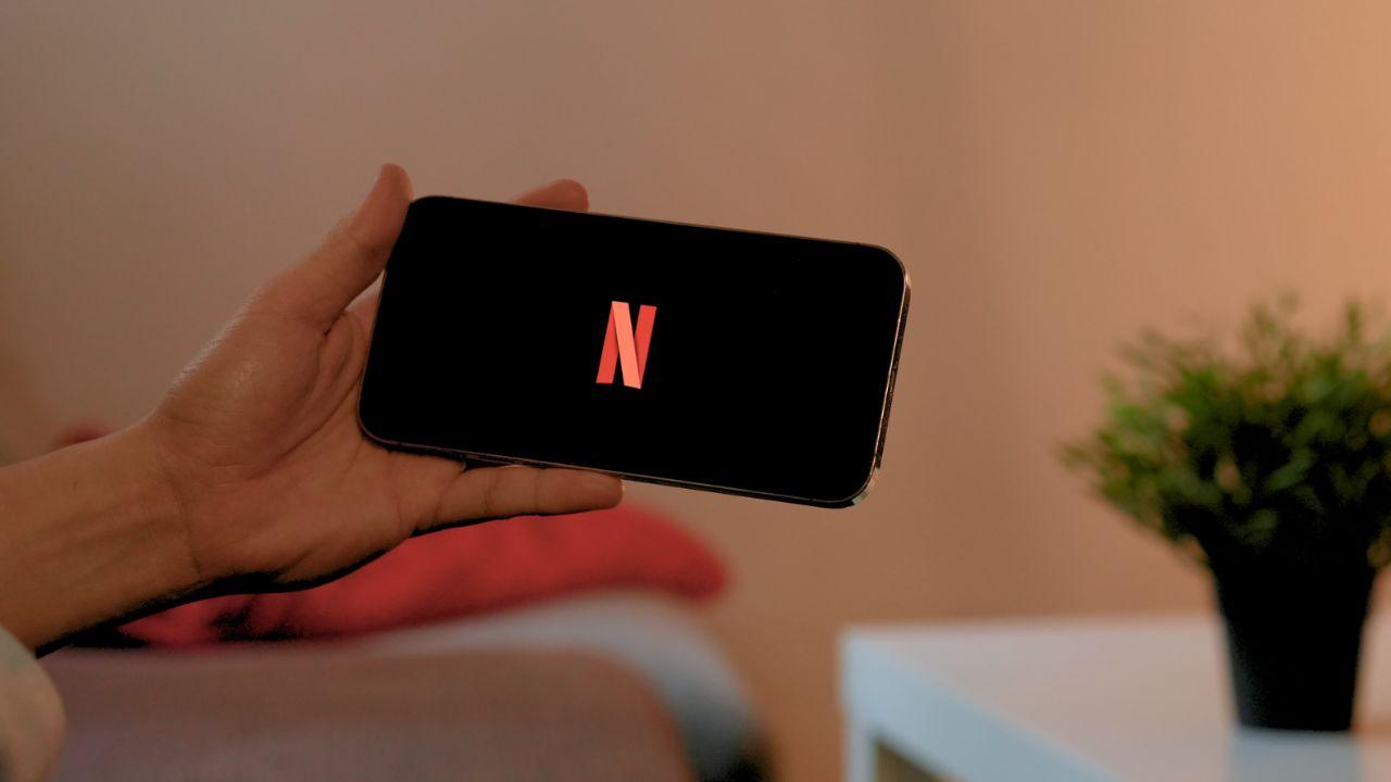Una mano sujetando un móvil con el logo de Netflix en la pantalla