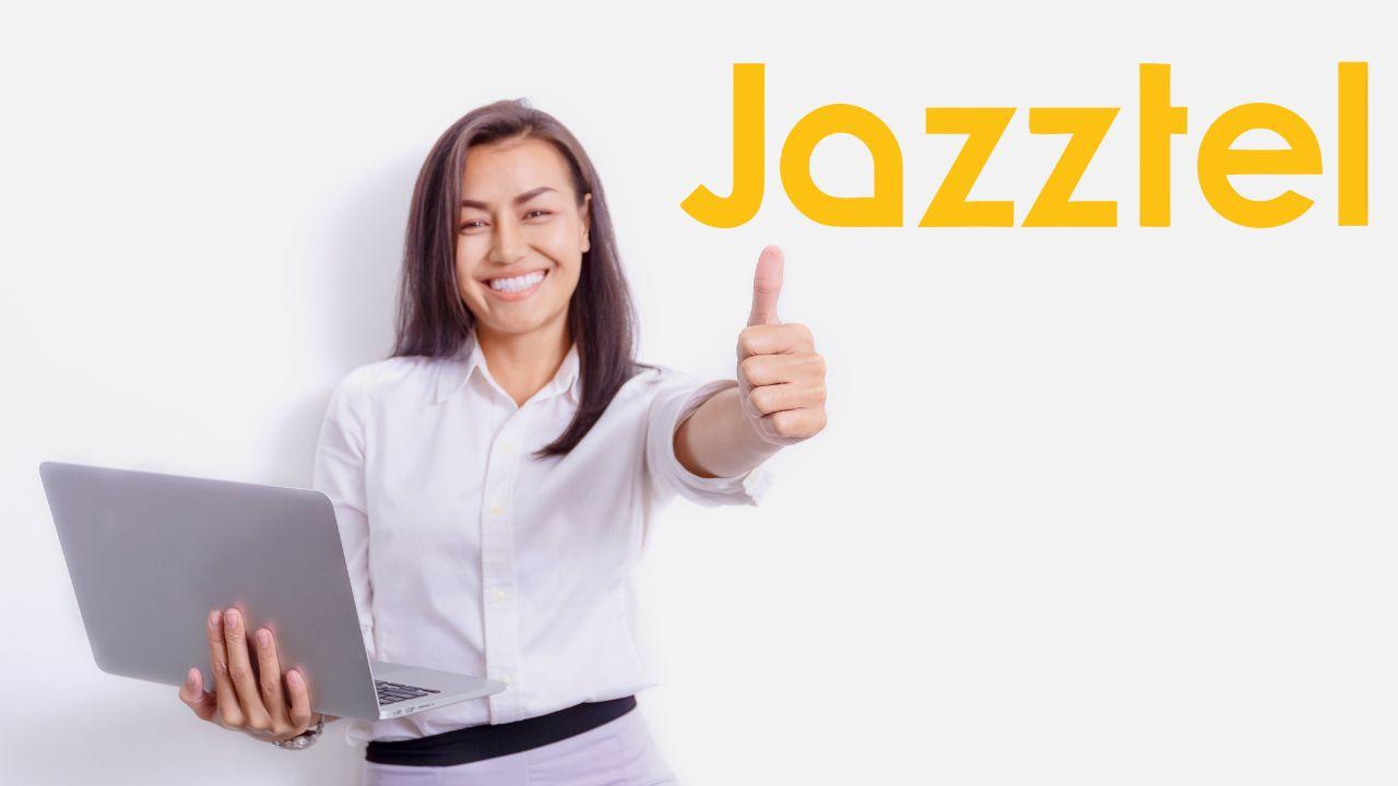 Una mujer contenta sujetando su ordenador portátil y el logo de Jazztel