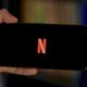 Un usuario sujeta un móvil con el logo de Netflix en la pantalla