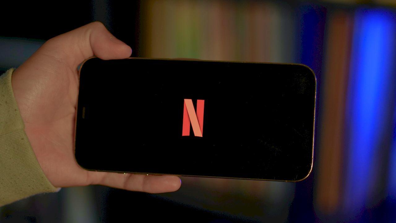 Un usuario sujeta un móvil con el logo de Netflix en la pantalla