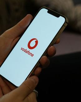 Sujetando un móvil con el logo de Vodafone en el centro